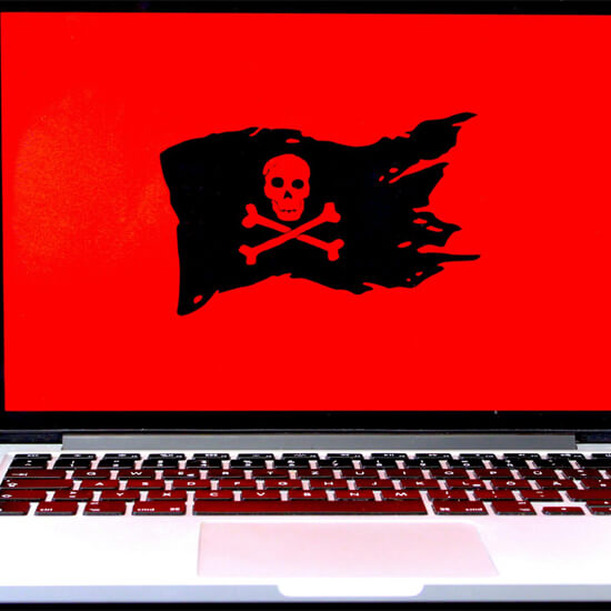 Dev Tech Solutions | One of our Insight Article images showing a Macbook with a red background colour on the screen with a black pirate symbol