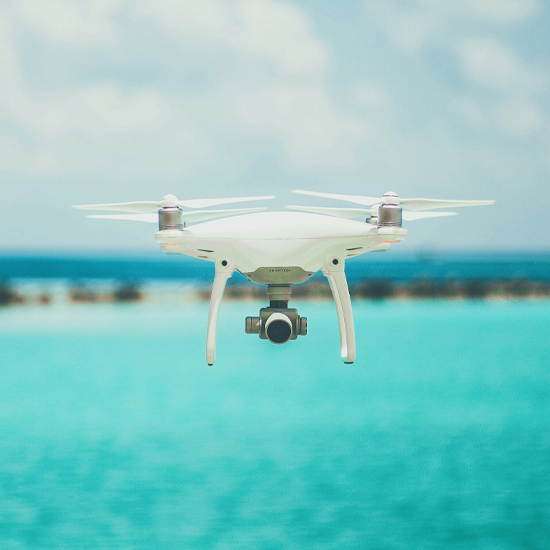 Dev Tech Solutions | showing a white drone recording mid flight